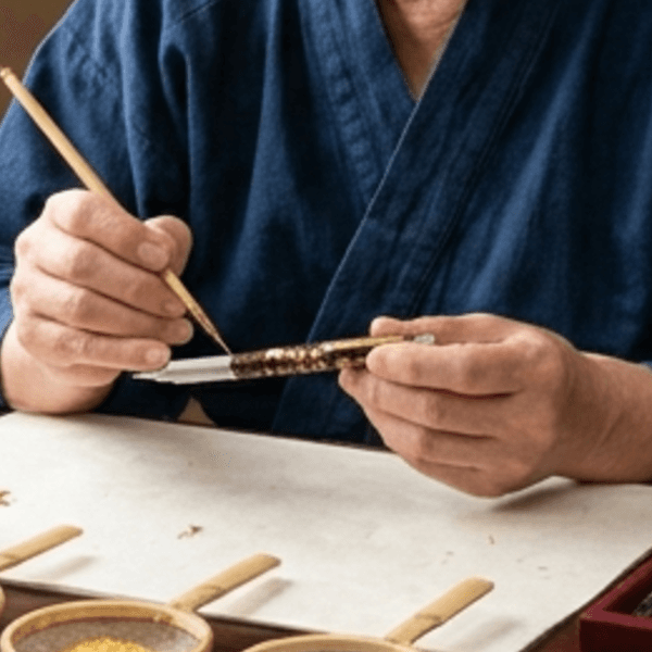 The master applying sprinkled gold with a maki-e brush